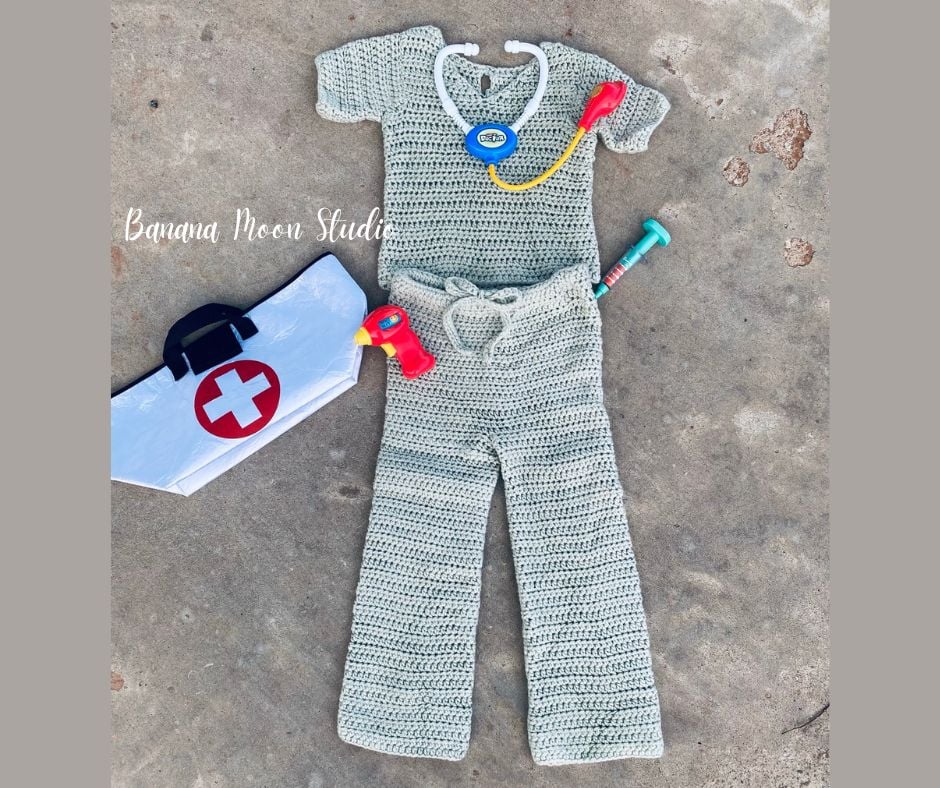 Pale green crochet costume pattern with top and drawstring pants along with children's doctor toys spread on bare cement. Text on the image reads: Banana Moon Studio