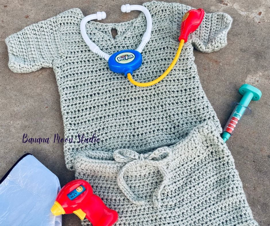 Crochet top and drawstring pants in pale green to look like children's scrubs along with doctor toys. Text on the image reads: Banana Moon Studio.