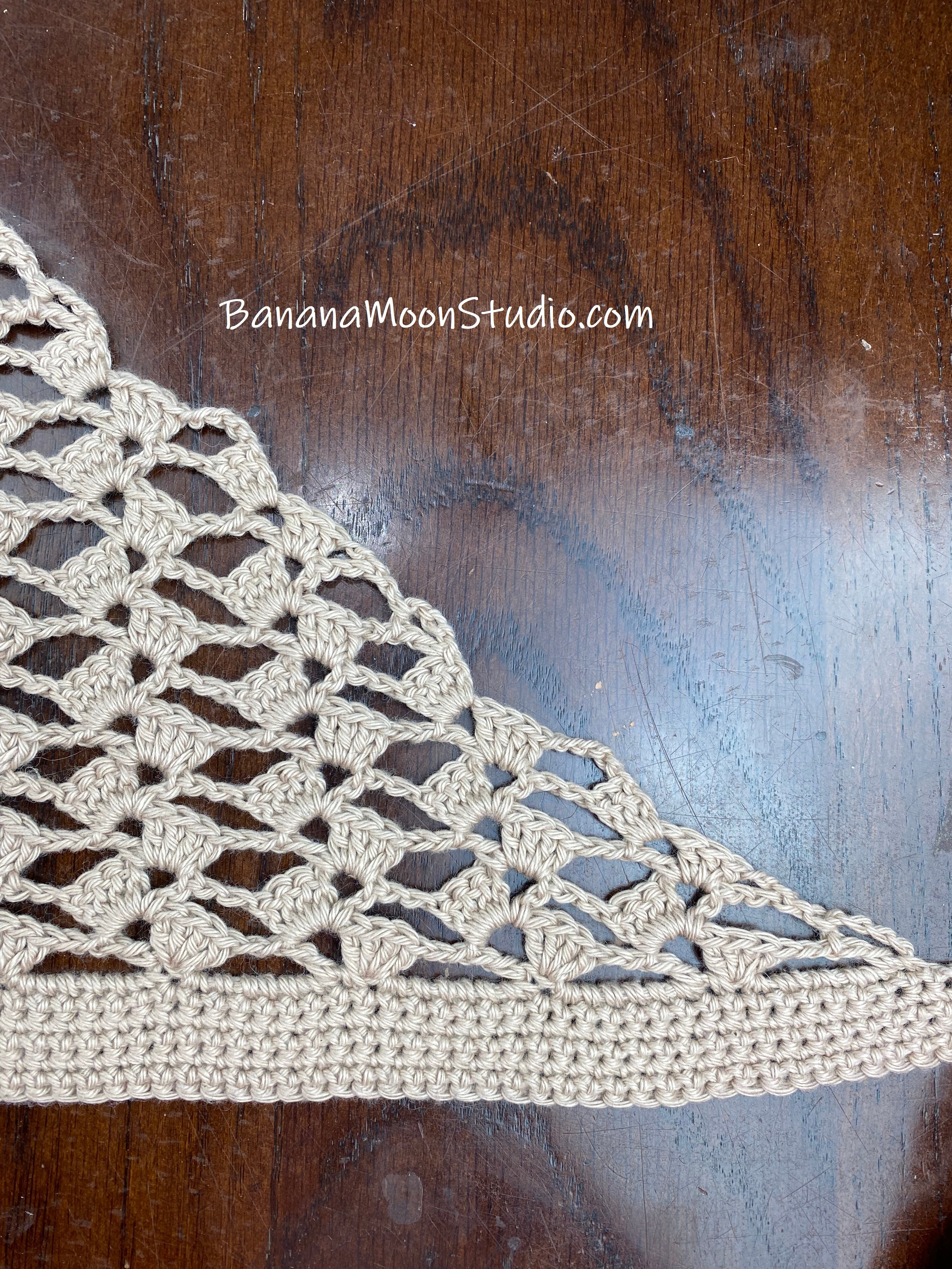 Close up photo of side shaping for a lace hair kerchief. Wooden table in the background. Text reads: BananaMoonStudio.com.