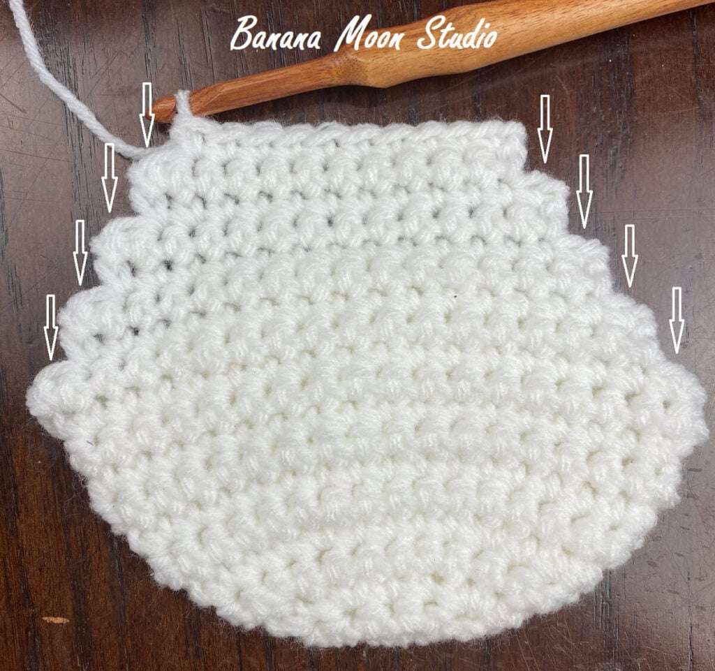 Short row Christmas stocking heel with arrows showing locations of skipped stitches to be worked into.