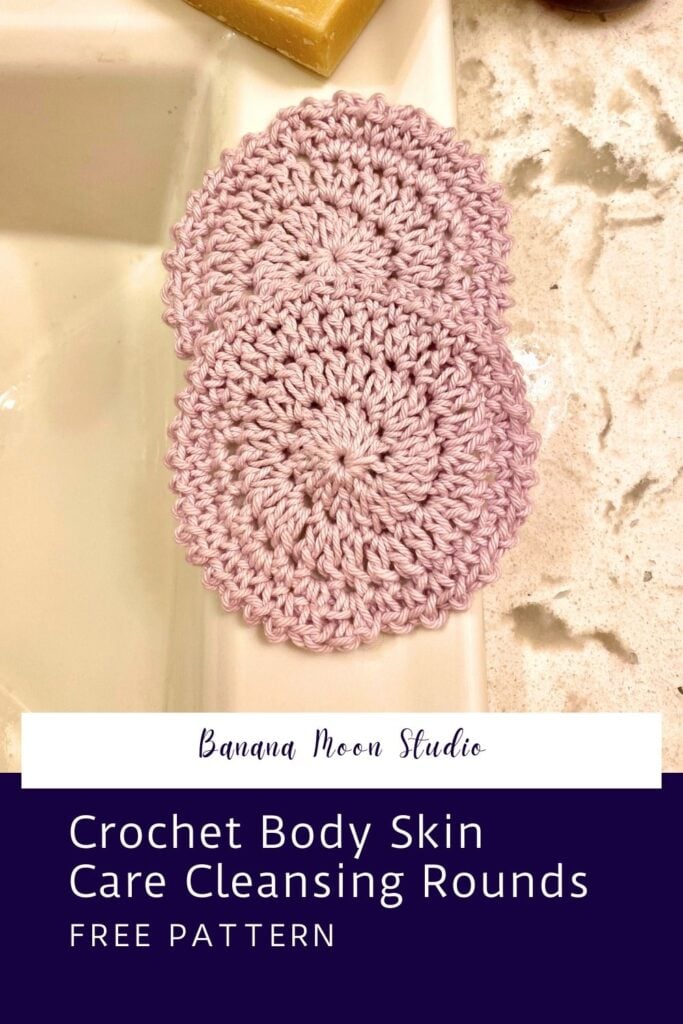 Two pale pink round crochet face scrubbies on the edge of a bathroom sink with a marble counter, and bar of soap in the background. White and purple panels with text read: Banana Moon Studio. Crochet body skin care cleansing rounds. Free pattern.