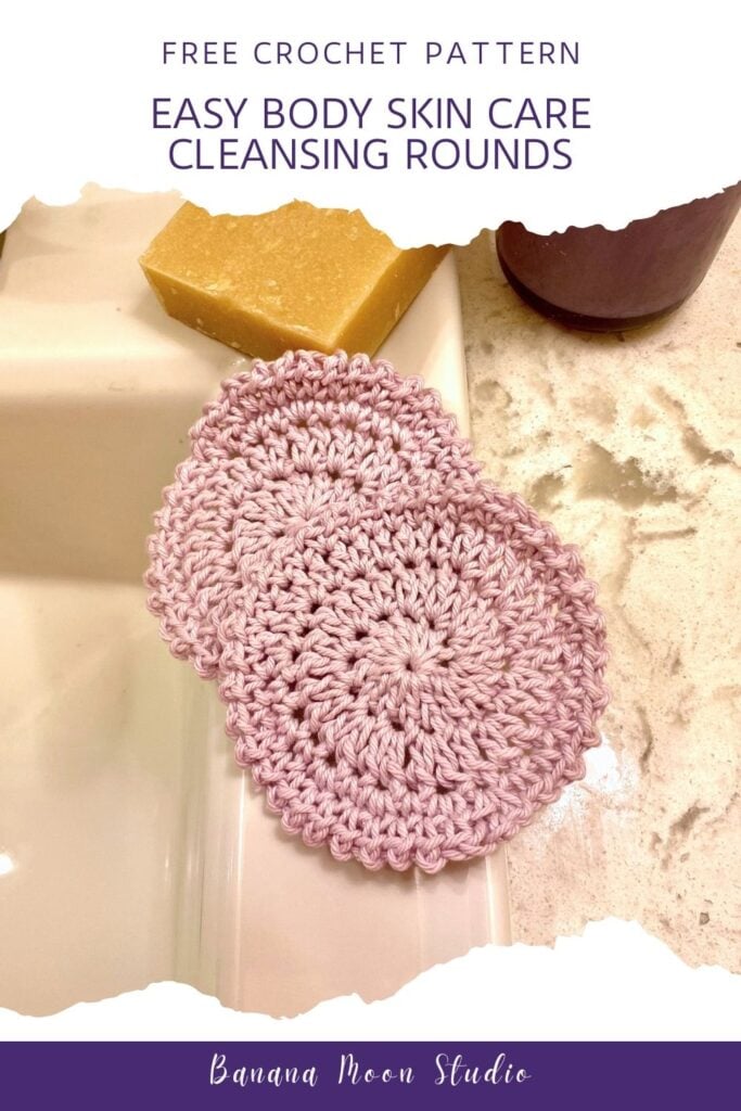 Two pale pink round crochet face scrubbies on the edge of a bathroom sink with a marble counter, and bar of soap in the background. White and purple panels with text read: Free crochet pattern. Easy body skin care cleansing rounds. Banana Moon Studio.