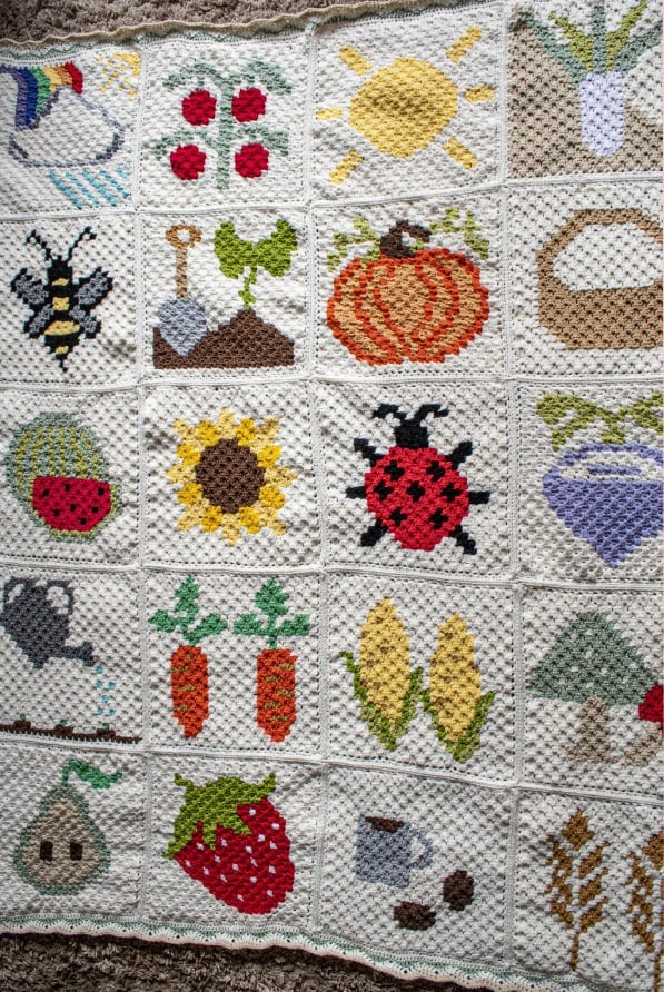 A C2C crochet blanket made of 20 squares, each featuring some aspect of gardening like weather, plants, insects, fruits, and vegetables.