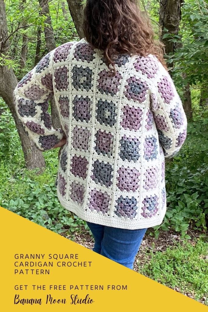 A woman standing in the woods wearing a granny square cardigan in cream and shades of purple and green over a green t-shirt and blue jeans. Text on the image reads: Banana Moon Studio. Yellow panel with text reads: Granny square cardigan crochet pattern. Get the free pattern from Banana Moon Studio.