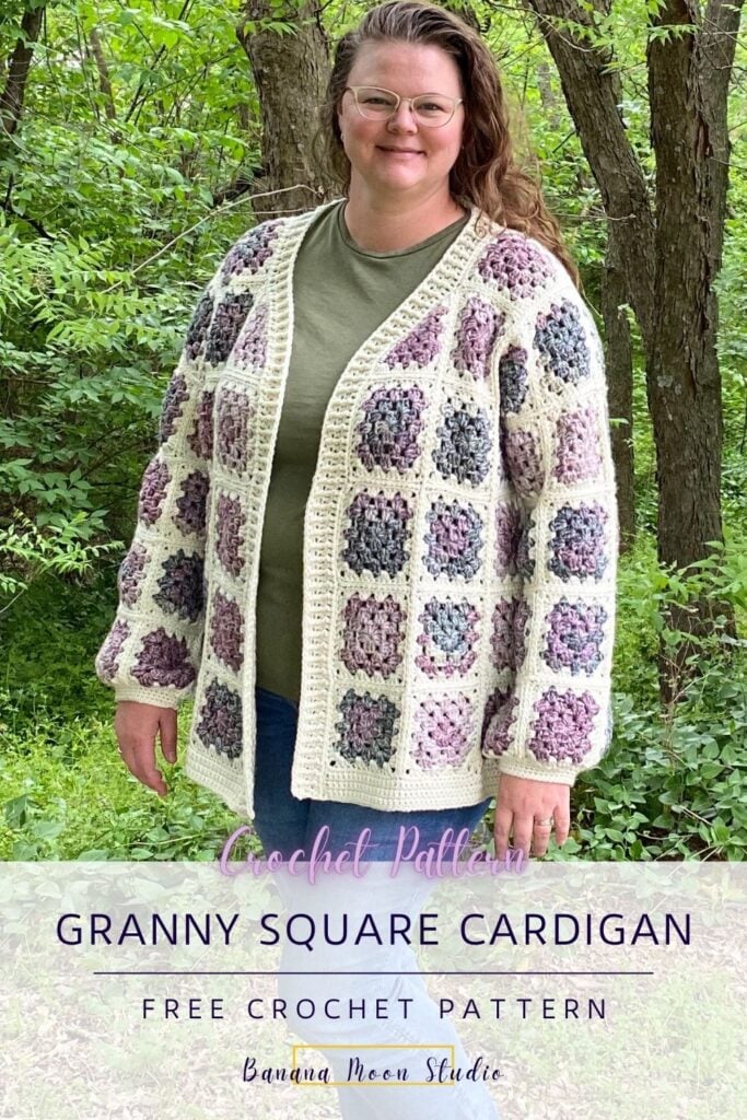 A woman standing in the woods wearing a granny square cardigan in cream and shades of purple and green over a green t-shirt and blue jeans. Text on the image reads: Banana Moon Studio. A white panel with text reads: Granny square cardigan. Free crochet pattern. Banana Moon Studio.