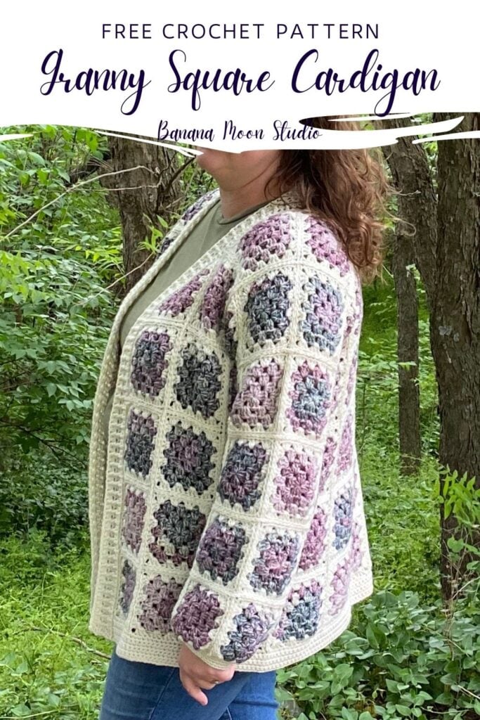 A woman standing in the woods wearing a granny square cardigan in cream and shades of purple and green over a green t-shirt and blue jeans. Text on the image reads: Banana Moon Studio. White panel with text reads: Free crochet pattern. Granny Square Cardigan. Banana Moon Studio.