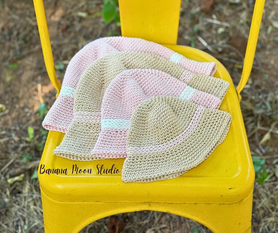 Four crochet bucket hats in pale pink and beige lying flat on a bright yellow chair. Text on the image reads: Banana Moon Studio.