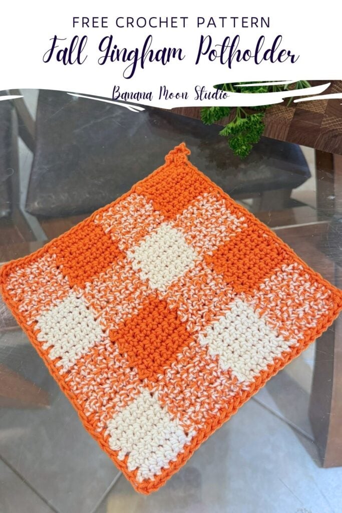 Orange and white gingham crochet pot holder lying flat on a glass table top. a panel with text reads: Free crochet pattern, fall gingham potholder, banana moon studio.