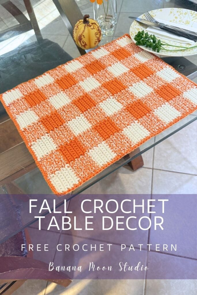 Fall crochet placemat in a gingham design on a glass table top. A panel with text reads: Fall crochet table decor, free crochet pattern, banana moon studio.