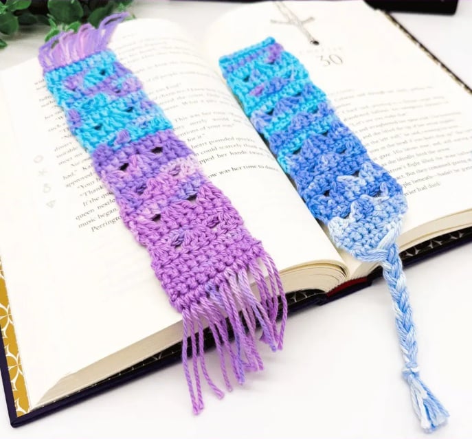 Blue and purple crochet bookmarks lay inside an open book.