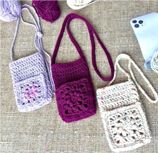 Three crochet phone cases, each with a long crochet strap and a pretty granny square pocket.