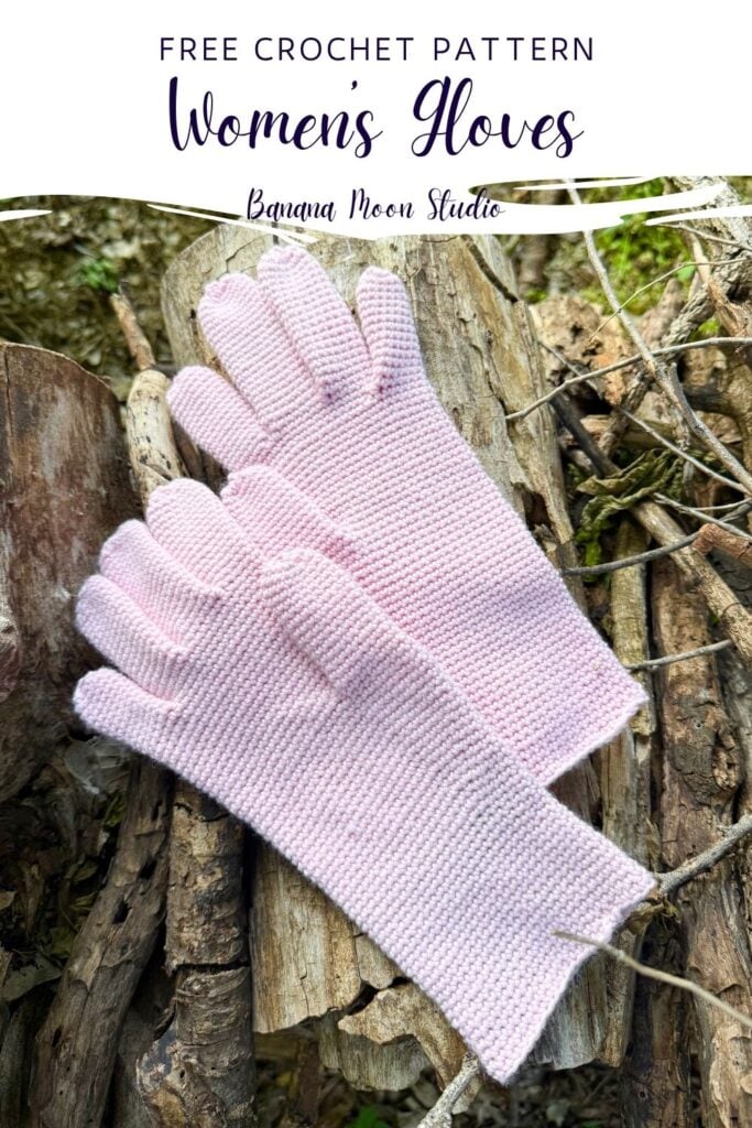 A pair of pink crochet gloves with fingers lies flat on a wood pile. A panel with text reads: Free crochet pattern, women's gloves, banana moon studio.