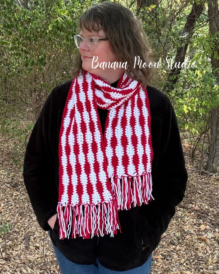 A woman stands outside wearing a striped crochet scarf over a black jacket. Text on the image reads: Banana Moon Studio.