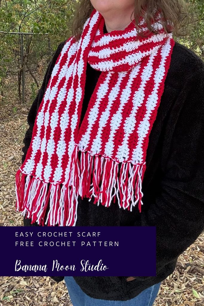 A woman stands outside wearing a striped red and white crochet scarf with fringe over a black jacket. A panel with text reads: Easy crochet scarf, free crochet pattern, banana moon studio.