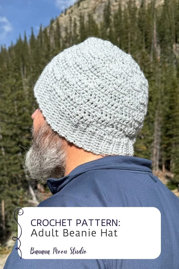 A bearded man stands outside facing away. He wears a gray crochet beanie. A panel with text reads: Crochet pattern, adult beanie hat, banana moon studio.