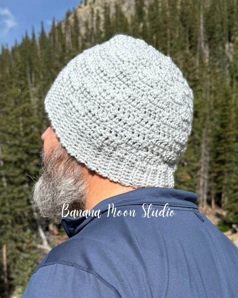 A bearded man faces away from the viewer. He wears a crochet beanie in light gray. Text on the image reads: Banana Moon Studio.