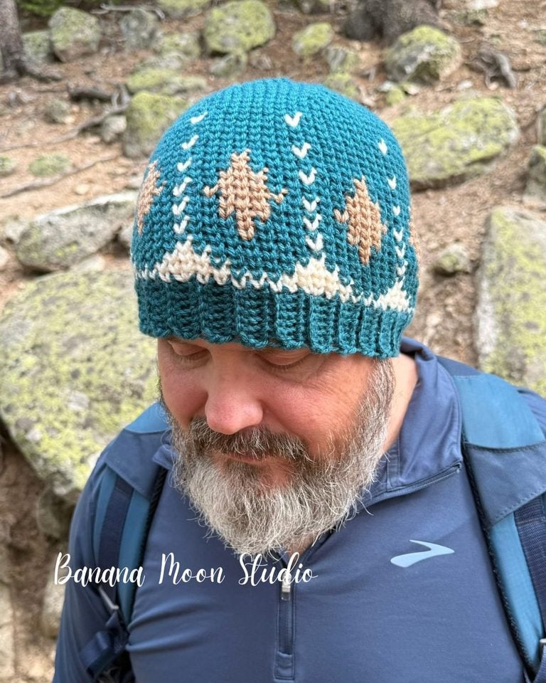 A bearded man stands outside. He wears a fair isle style crochet beanie. Text on the image reads: Banana Moon Studio.